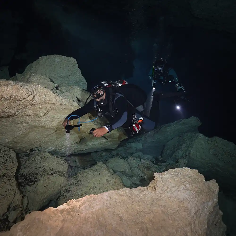 Scuba divers swimming though Cenote Chac Mool.